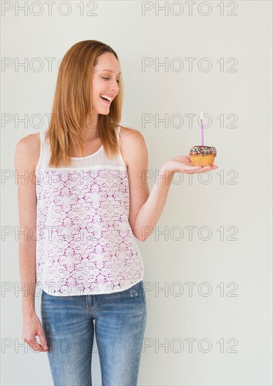 Woman holding birthday cupcake.