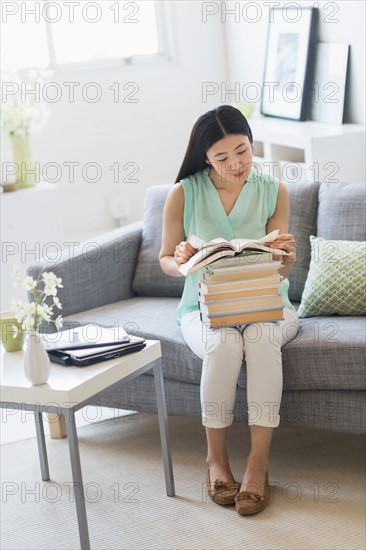 Woman with stack of books at home.