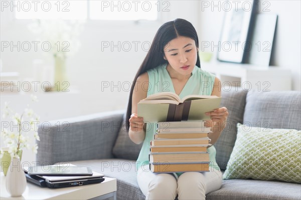 Woman with stack of books at home.