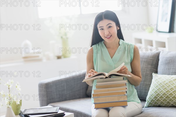 Woman with stack of books at home.