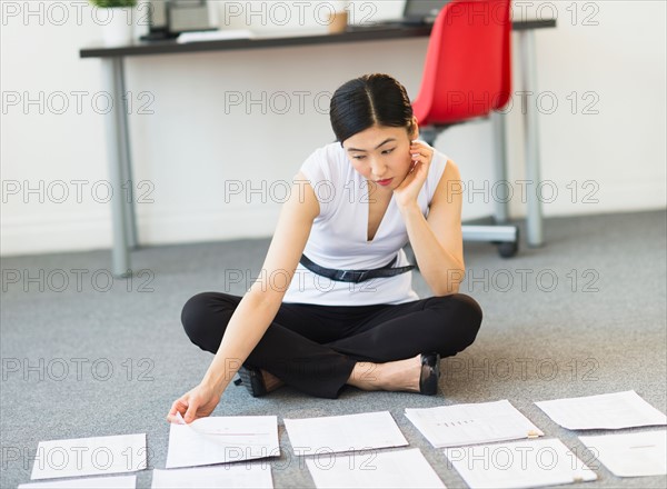 Businesswoman organizing paperwork on floor.