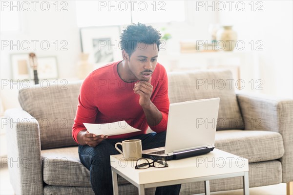 Man sitting on sofa and using laptop.