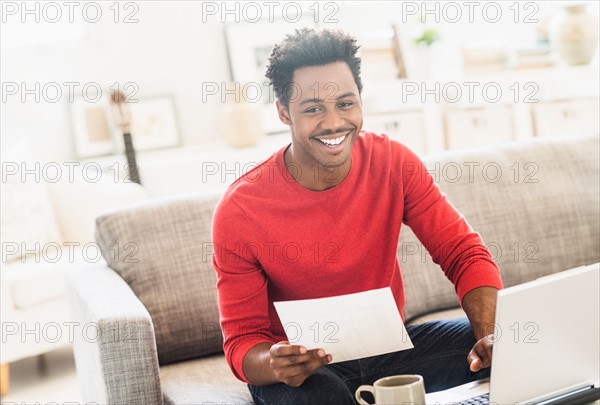 Man sitting on sofa and using laptop.