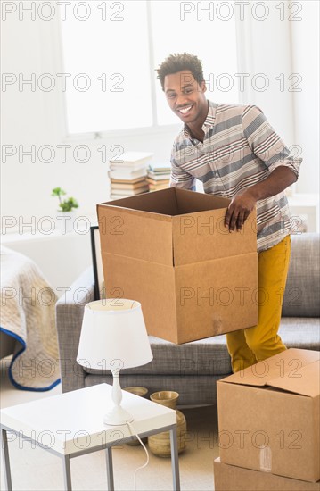 Man holding cardboard box in living room.