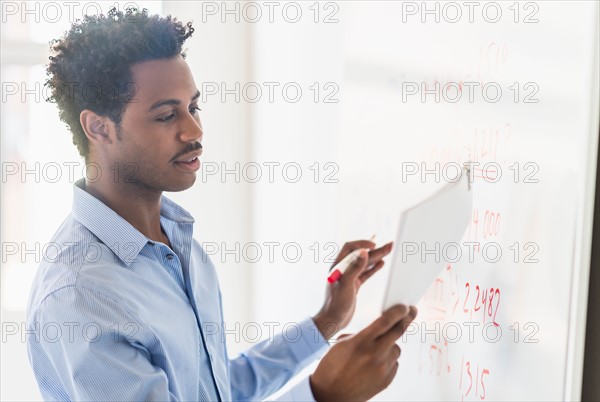 Businessman writing on whiteboard.