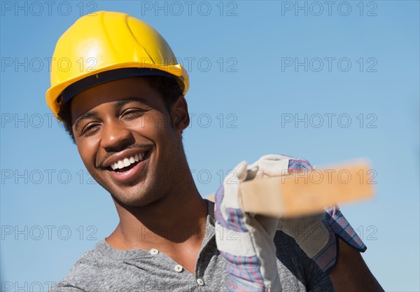 Construction worker carrying plank.