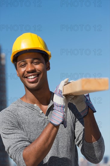 Construction worker carrying plank.