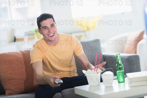 Man eating take out meal and watching television.