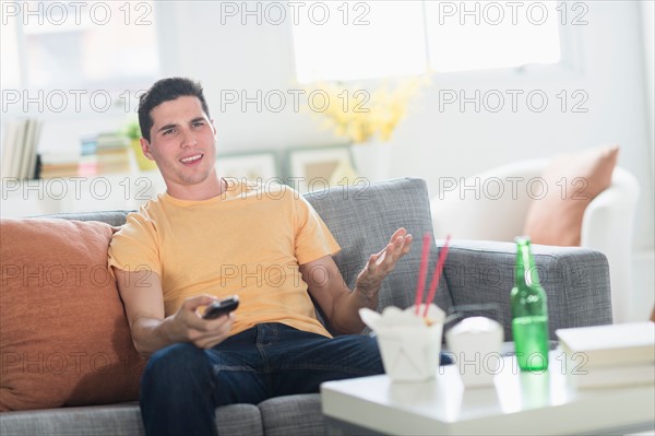 Man eating take out meal and watching television.