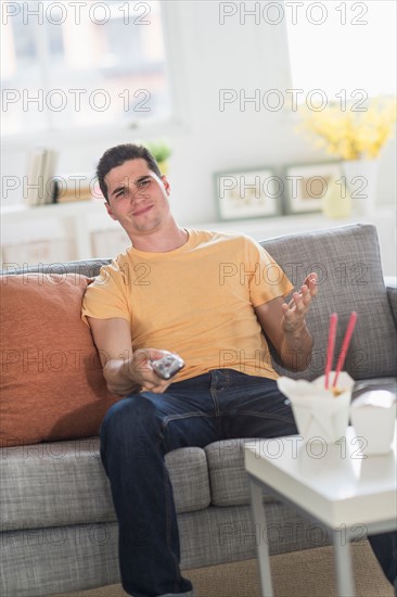 Man eating take out meal and watching television.