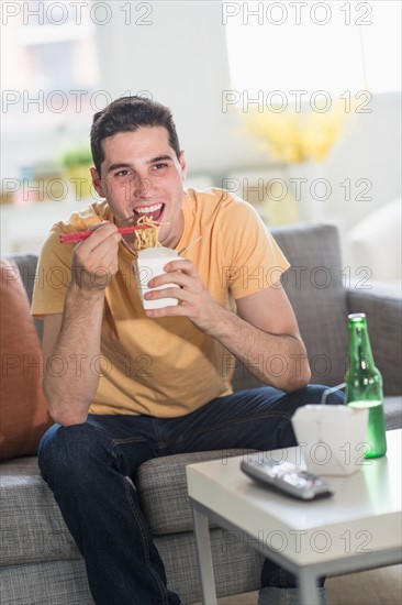 Man eating take out meal and watching television.