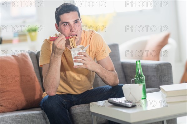 Man eating take out meal and watching television.