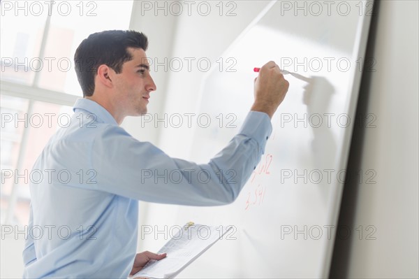 Businessman writing on whiteboard.
