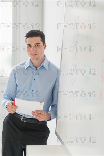 Businessman standing next to whiteboard.