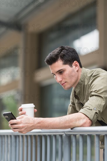 Man drinking coffee and text messaging.