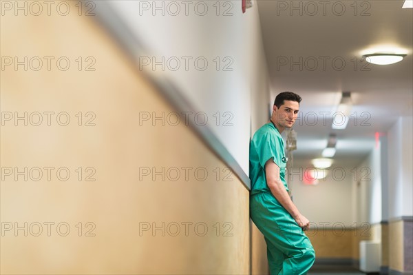 Tired doctor standing in hallway.