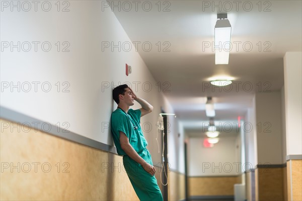 Tired doctor standing in hallway.