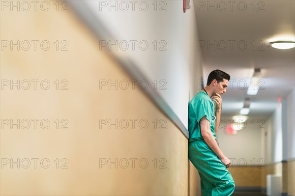 Tired doctor standing in hallway.
