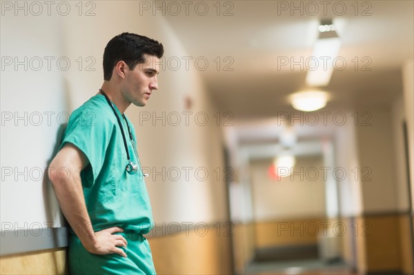 Tired doctor standing in hallway.