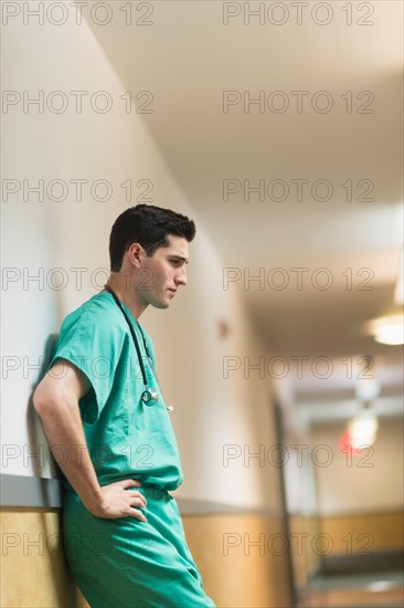 Tired doctor standing in hallway.