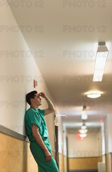Tired doctor standing in hallway.