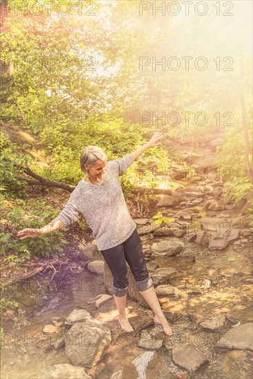 Central Park, New York City. Senior woman crossing stream.