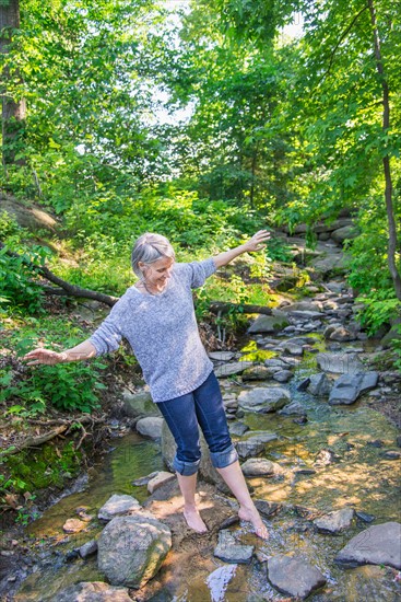 Central Park, New York City. Senior woman crossing stream.