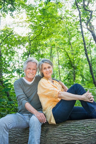 Central Park, New York City. Senior couple sitting on log in forest.