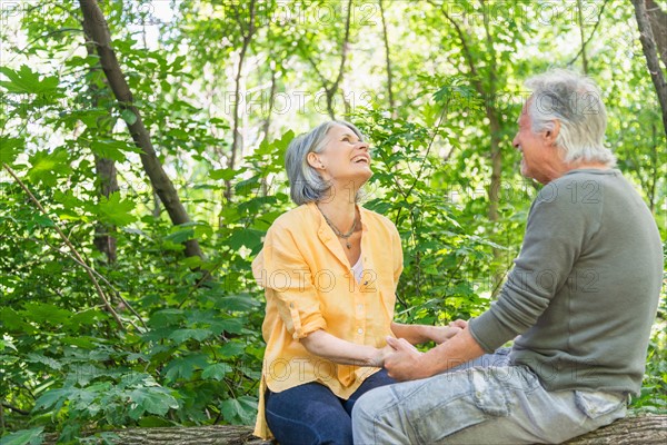 Central Park, New York City. Senior couple sitting on log in forest.