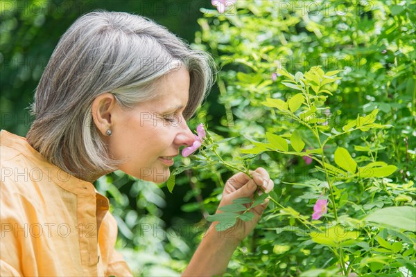 Senior woman smelling flower.