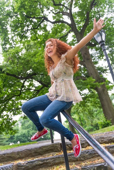 Central Park, New York City. Woman sliding on railing in park.