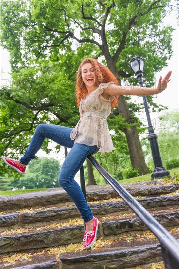 Central Park, New York City. Woman sliding on railing in park.