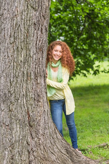 Woman leaning on tree in park.