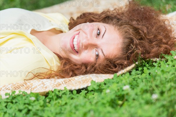 Portrait of young woman lying on grass in park.