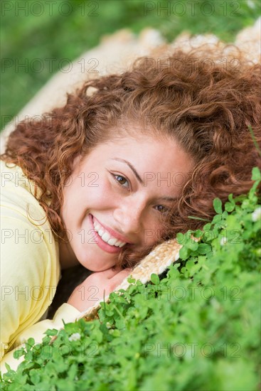 Portrait of young woman lying on grass in park.