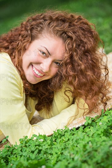 Portrait of young woman lying on grass in park.