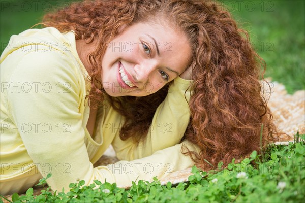 Woman lying on grass in park.