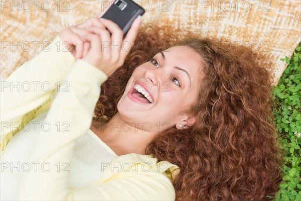 Woman lying on grass in park and using mobile phone.