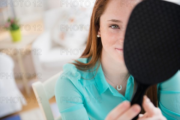 Teenage girl (14-15) with hand mirror