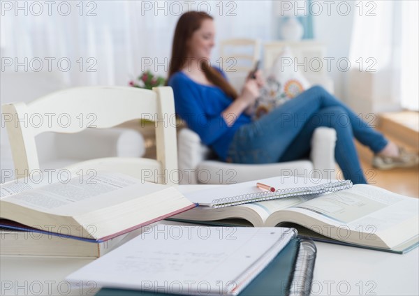 Teenage girl (14-15) text messaging in armchair