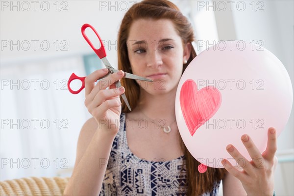 Teenage girl (14-15) holding balloon and scissors