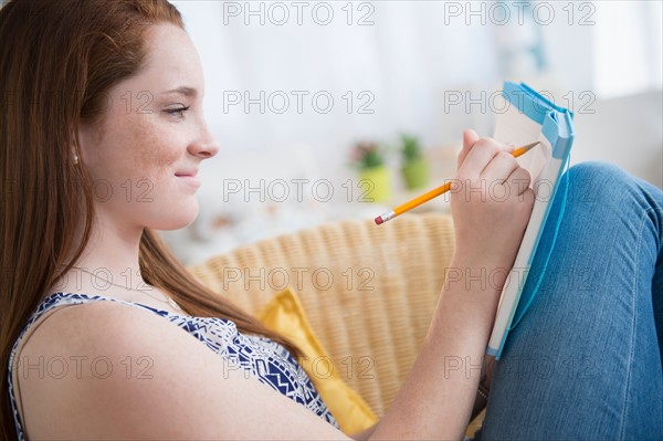Teenage girl (14-15) writing in notebook