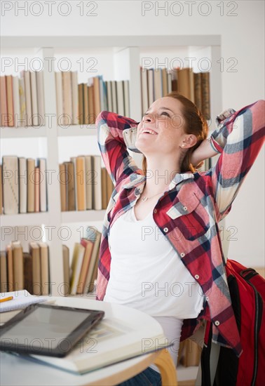 Teenage girl (14-15) stretching while studying