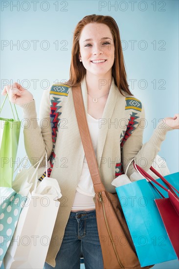 Teenage girl (14-15) carrying shopping bags, studio shot