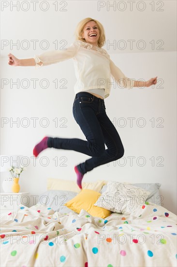 Young woman jumping on bed