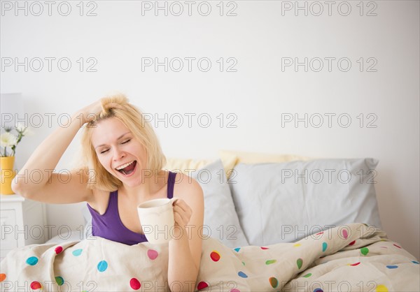 Young woman yawning in bed