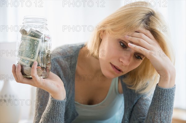 Young woman holding jar with banknotes