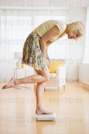 Woman weighing herself on scale