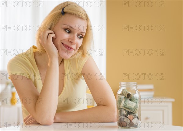 Portrait of woman looking at jar full of money