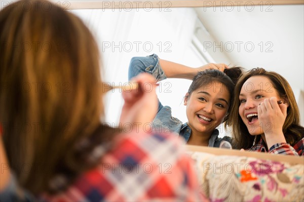 Young women doing make-up reflecting in mirror